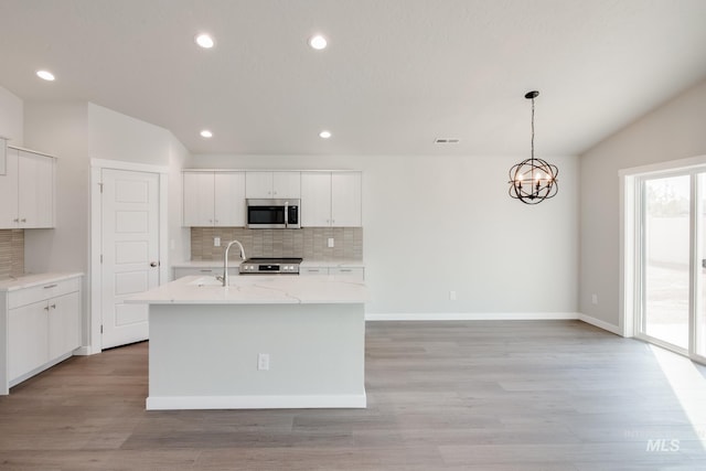 kitchen featuring white cabinetry, an island with sink, pendant lighting, stainless steel appliances, and backsplash