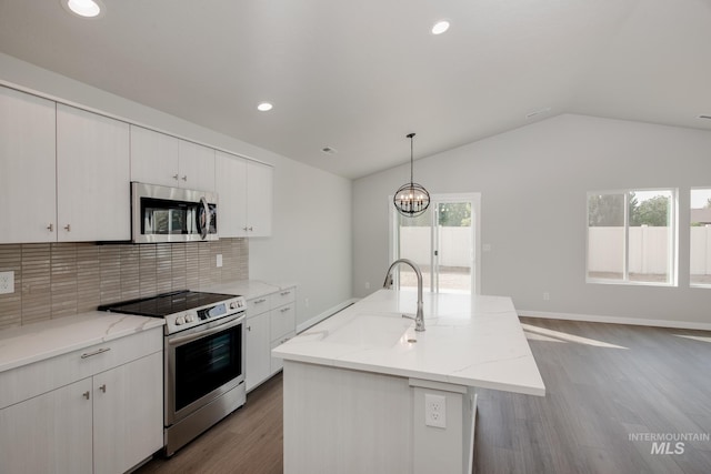 kitchen with tasteful backsplash, hanging light fixtures, stainless steel appliances, and an island with sink