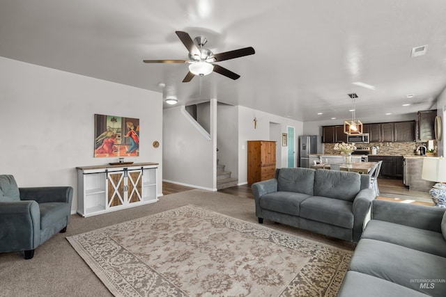 living room with visible vents, ceiling fan, baseboards, and stairs