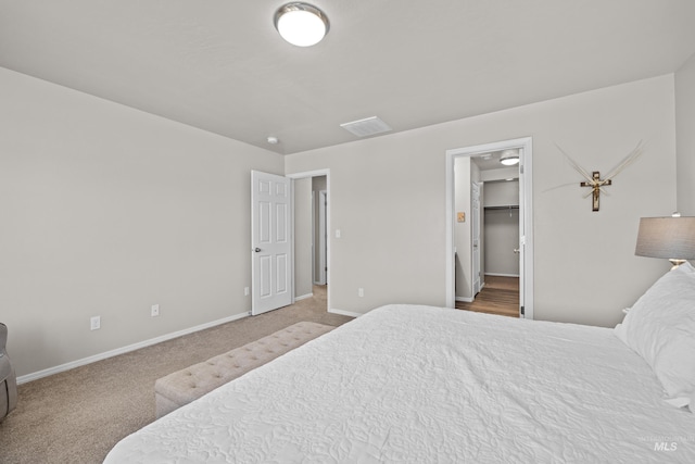 bedroom featuring carpet floors, a walk in closet, and baseboards