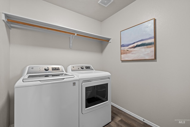 clothes washing area with laundry area, dark wood-style flooring, visible vents, baseboards, and washer and dryer