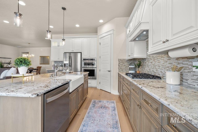 kitchen featuring tasteful backsplash, a sink, light wood-style floors, stainless steel appliances, and white cabinetry