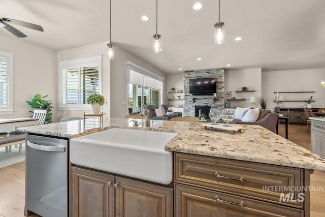 kitchen with dishwasher, open floor plan, a sink, and light wood-type flooring
