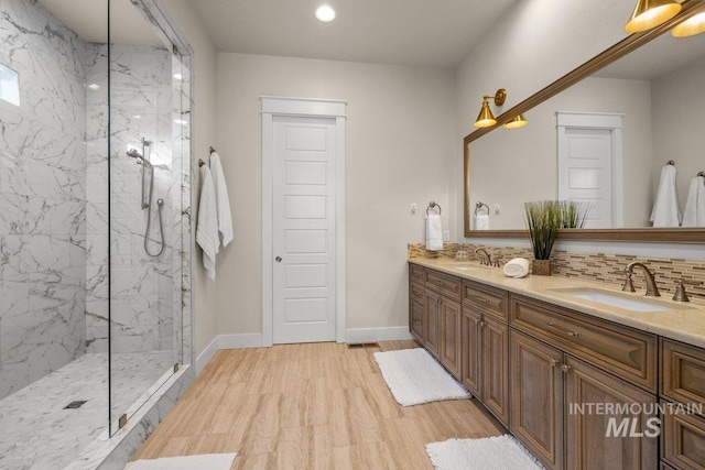 full bathroom with backsplash, double vanity, a marble finish shower, and a sink