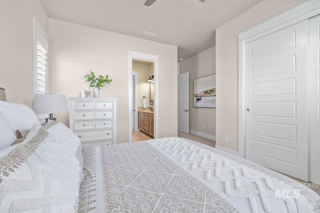 bedroom with visible vents, baseboards, and ensuite bathroom
