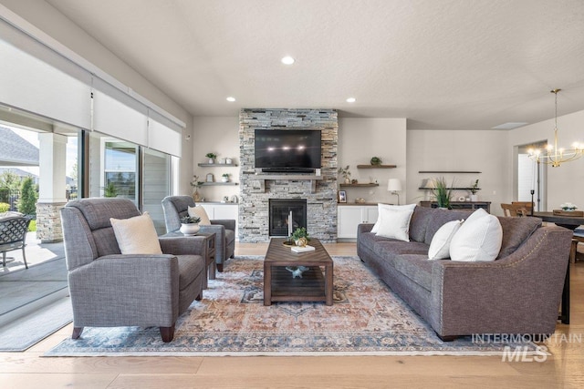 living room featuring recessed lighting, light wood-style floors, a chandelier, and a fireplace