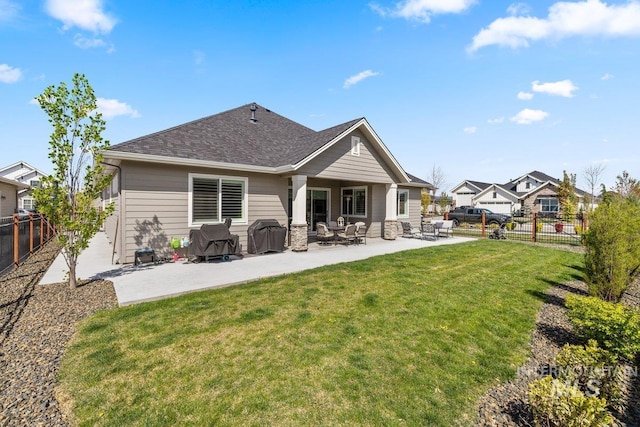 rear view of property featuring a lawn, a patio, a fenced backyard, and a shingled roof