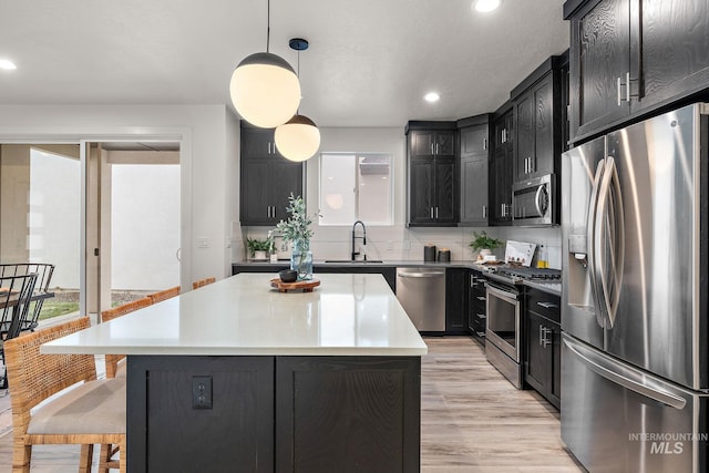 kitchen featuring sink, a center island, backsplash, pendant lighting, and appliances with stainless steel finishes