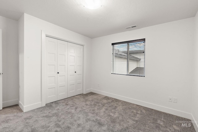 unfurnished bedroom with a closet and light colored carpet