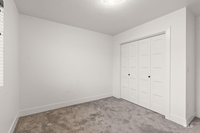 unfurnished bedroom with a closet and light colored carpet