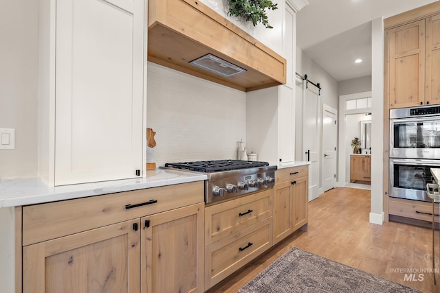 6635 Big Wood Way, Star, ID 83669 - kitchen with appliances with stainless steel finishes, a barn door, light brown cabinets, light wood-type flooring, and recessed lighting