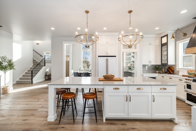 kitchen with a chandelier, premium appliances, a center island, and light wood-style floors