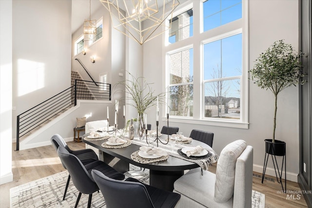 dining area featuring stairs, a high ceiling, wood finished floors, and baseboards