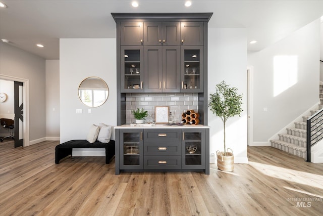 bar with baseboards, light wood-style flooring, recessed lighting, decorative backsplash, and stairs