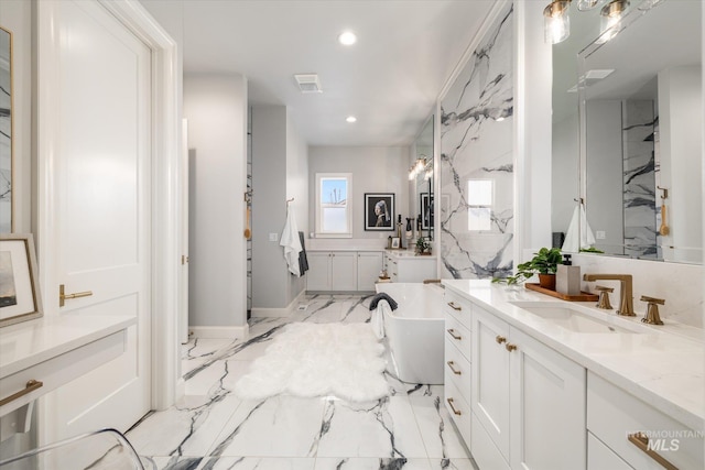 full bath with visible vents, a freestanding tub, marble finish floor, a sink, and recessed lighting