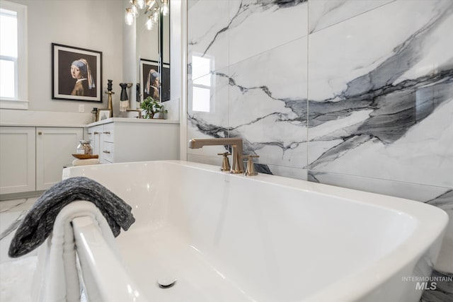 full bathroom with a soaking tub, marble finish floor, and vanity