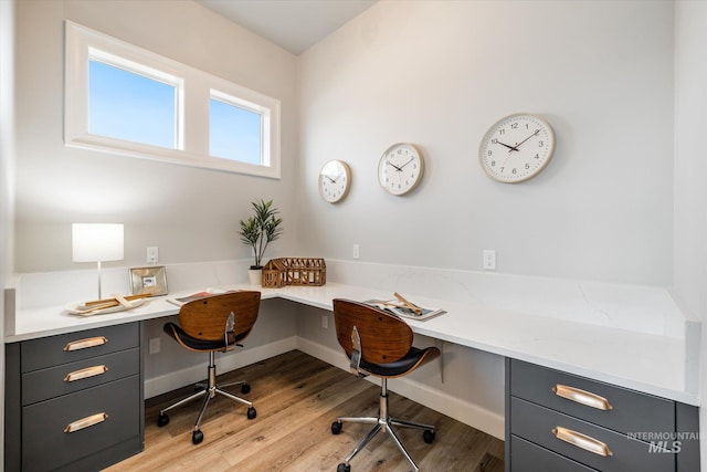 home office with built in desk, baseboards, and light wood-style floors