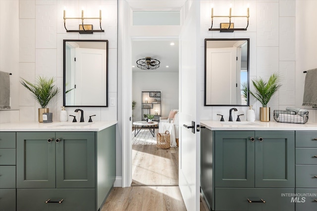 ensuite bathroom with two vanities, wood finished floors, and a sink