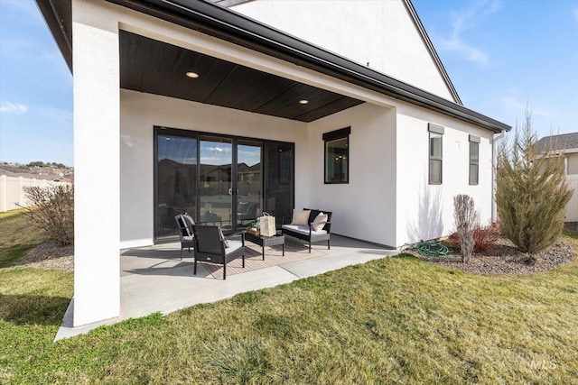 rear view of property featuring a patio area, a lawn, and stucco siding