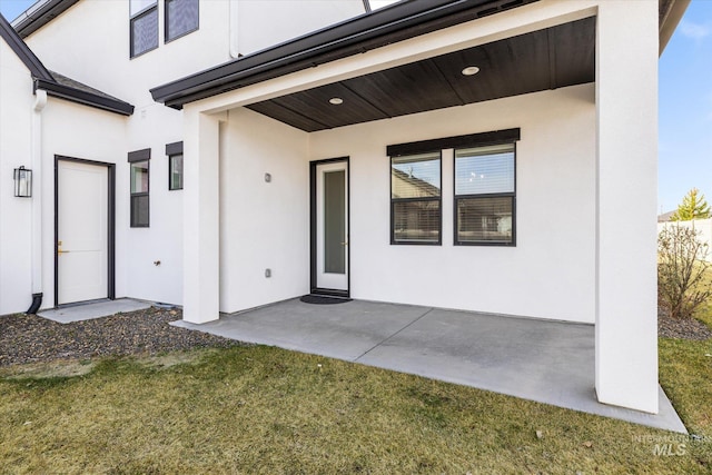 doorway to property featuring stucco siding and a patio area