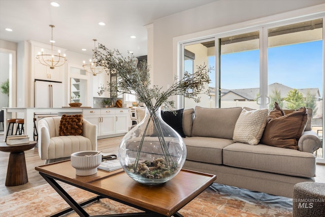 living room featuring recessed lighting, light wood-type flooring, and an inviting chandelier