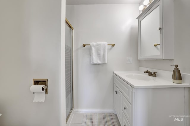 full bath featuring a shower with shower door, tile patterned flooring, vanity, and baseboards