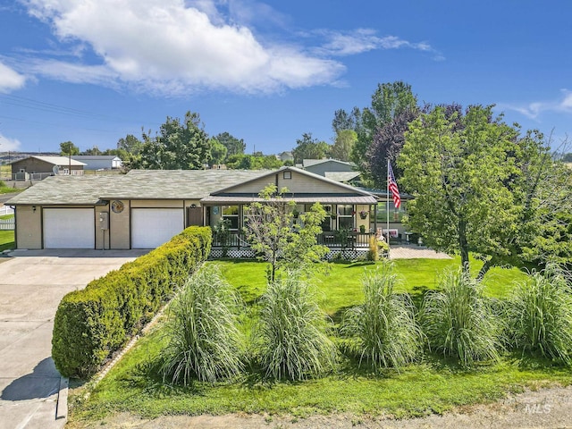 view of front of house featuring a garage, a front yard, a porch, and driveway