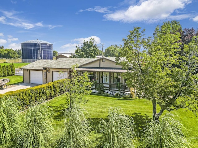 view of front of property featuring a front yard, covered porch, an attached garage, and concrete driveway