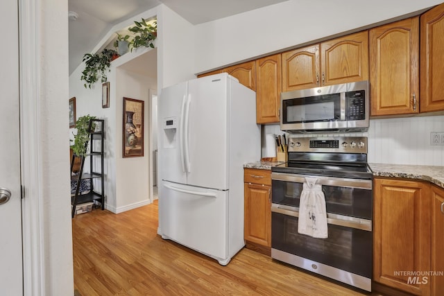 kitchen with baseboards, appliances with stainless steel finishes, brown cabinets, light stone counters, and light wood-type flooring