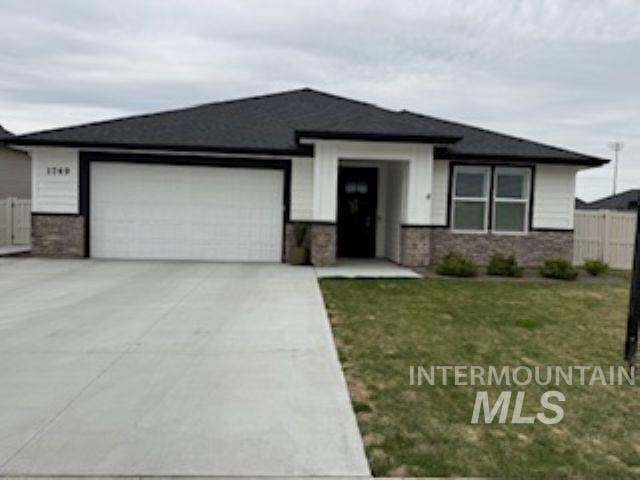 prairie-style house with driveway, a front lawn, fence, and an attached garage