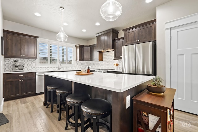 kitchen with dark brown cabinets, light wood-style flooring, and stainless steel appliances