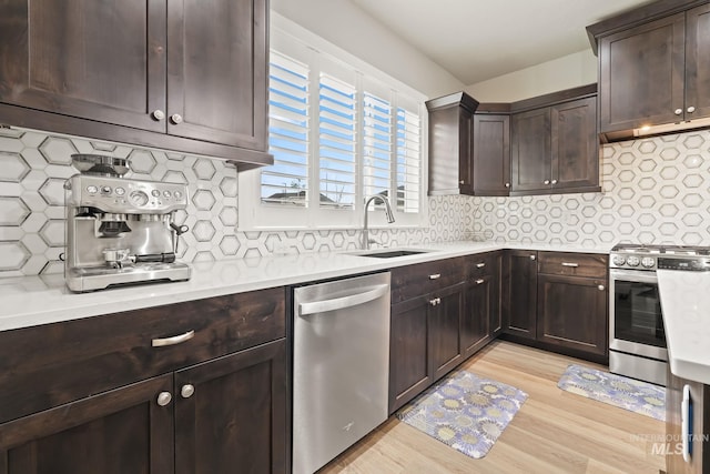 kitchen with light countertops, dark brown cabinets, appliances with stainless steel finishes, a sink, and backsplash