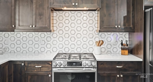 kitchen featuring light countertops, tasteful backsplash, gas stove, under cabinet range hood, and dark brown cabinetry