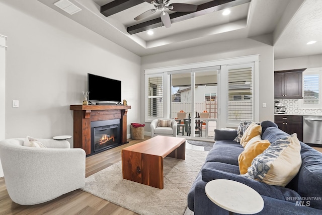 living room with a glass covered fireplace, beamed ceiling, light wood-style floors, ceiling fan, and recessed lighting