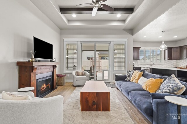 living room featuring recessed lighting, light wood-style flooring, a glass covered fireplace, and a ceiling fan
