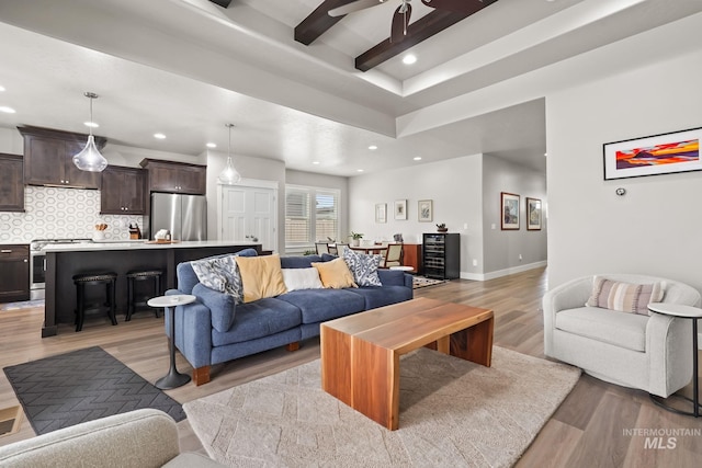 living area with baseboards, ceiling fan, recessed lighting, beam ceiling, and light wood-style floors