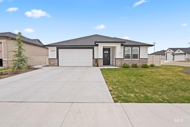 prairie-style house with a front lawn, fence, stone siding, and a garage