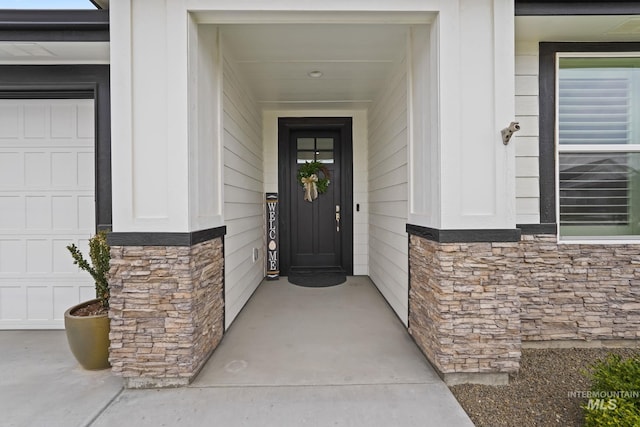 property entrance featuring stone siding and a garage