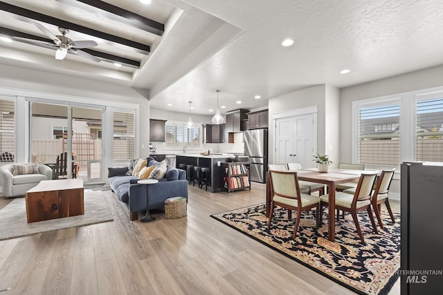 dining area featuring a ceiling fan, plenty of natural light, light wood finished floors, and a textured ceiling