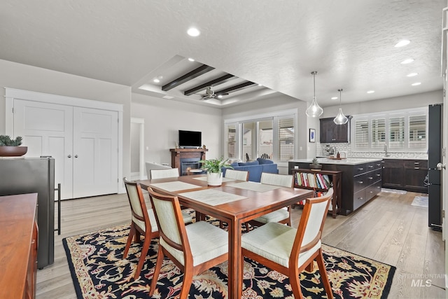 dining room featuring recessed lighting, a glass covered fireplace, light wood-style floors, and a textured ceiling