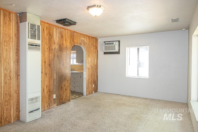 402 S Hayes, Emmett, ID 83617 - unfurnished bedroom with a heating unit, a wall mounted AC, carpet, wood walls, and arched walkways
