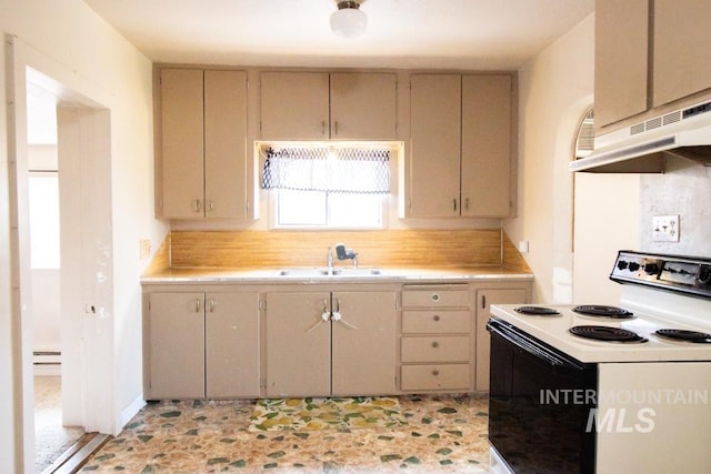 402 S Hayes, Emmett, ID 83617 - kitchen featuring white range with electric stovetop, light countertops, a baseboard radiator, under cabinet range hood, and cream cabinets