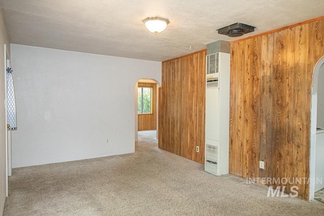 402 S Hayes, Emmett, ID 83617 - empty room featuring arched walkways, a heating unit, carpet flooring, and wood walls