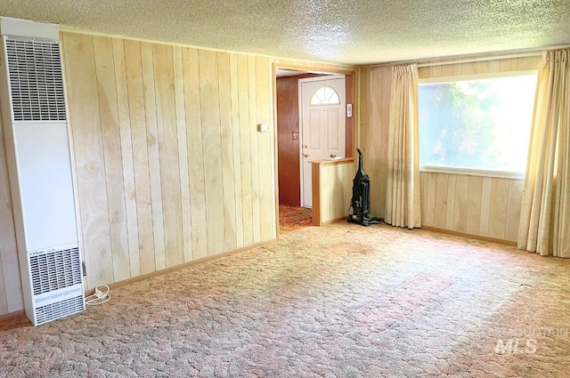 545 Madison St, Twin Falls, ID 83301 - carpeted empty room with a heating unit, wooden walls, a textured ceiling, and baseboards