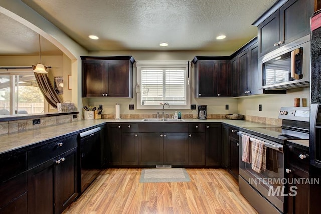 kitchen with a sink, stainless steel appliances, light wood-style floors, and a textured ceiling