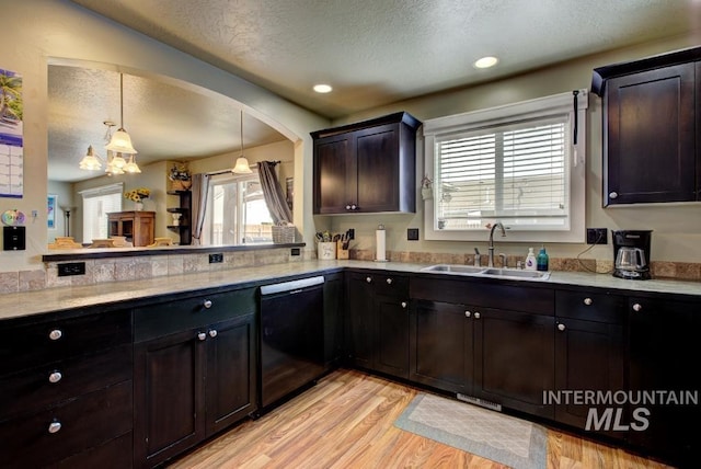 kitchen featuring a textured ceiling, black dishwasher, light wood finished floors, and a sink