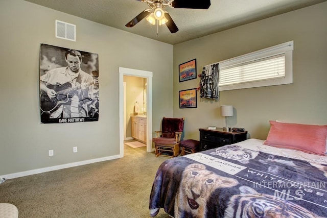 carpeted bedroom with visible vents, a textured ceiling, connected bathroom, baseboards, and ceiling fan