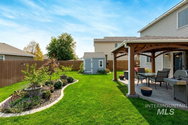 view of yard featuring an outbuilding, a fenced backyard, a shed, and a patio area