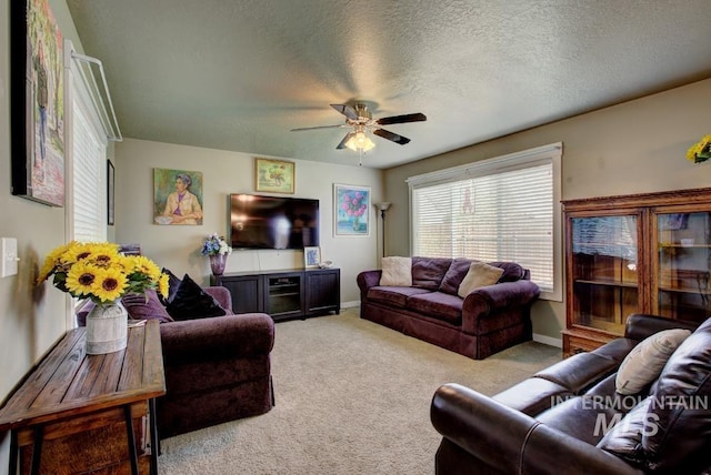 carpeted living area featuring baseboards, a textured ceiling, and ceiling fan