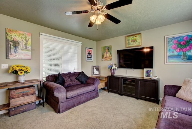 living room featuring light carpet, a textured ceiling, and ceiling fan